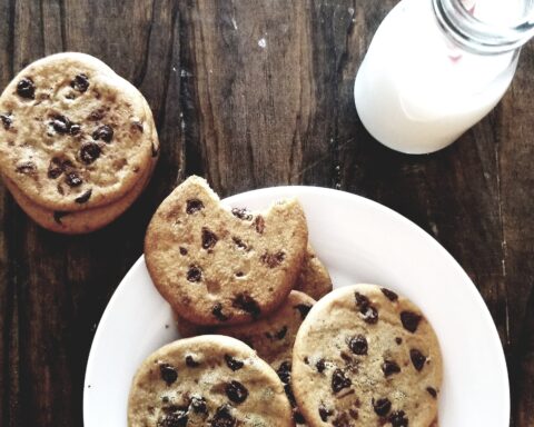 A plate of chocolate chip cookies and a bottle of milk