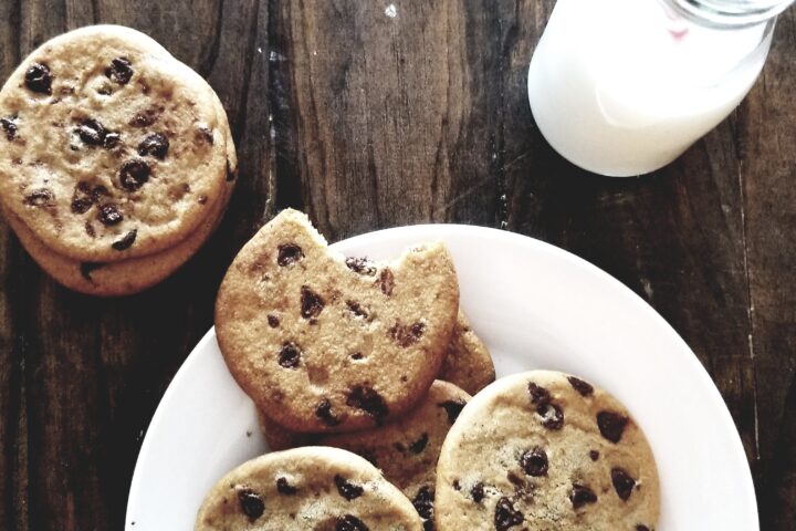 A plate of chocolate chip cookies and a bottle of milk