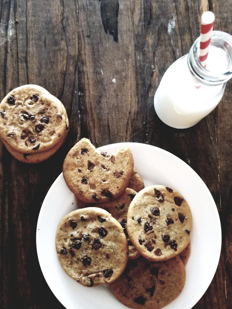 A plate of chocolate chip cookies and a bottle of milk